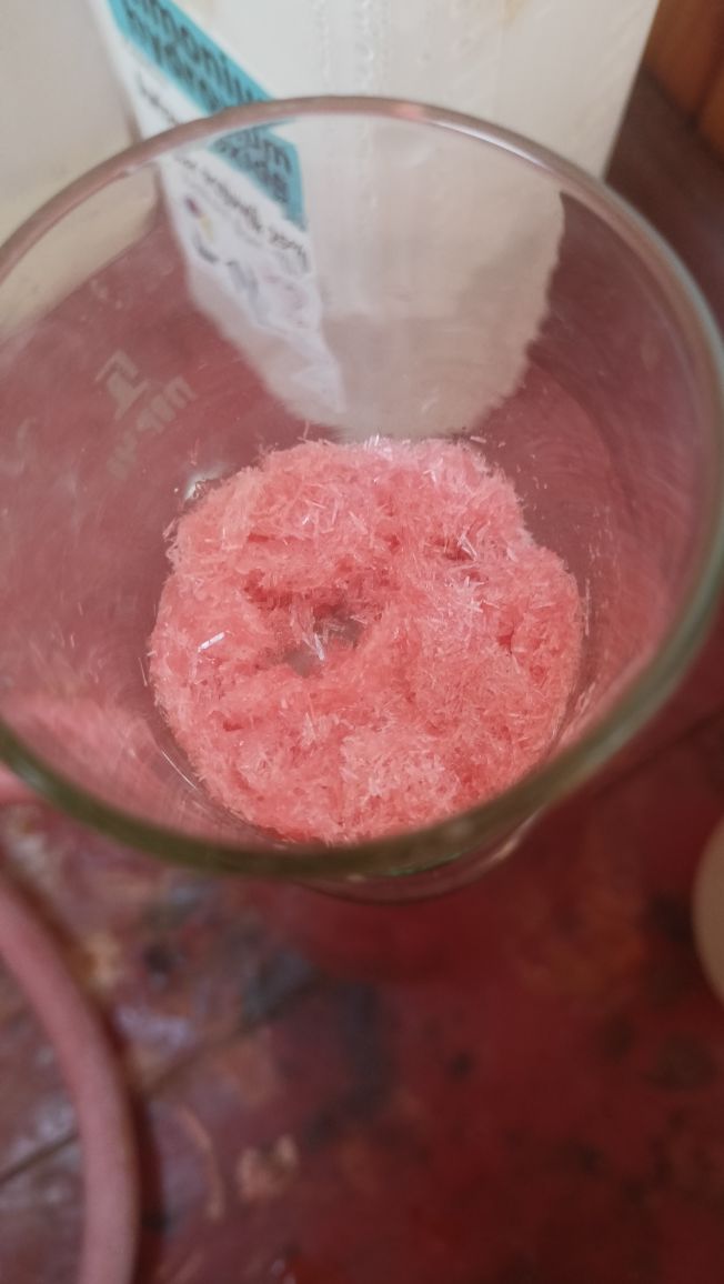 Wet Pink Needle-like crystals in a vacuum filter funnel