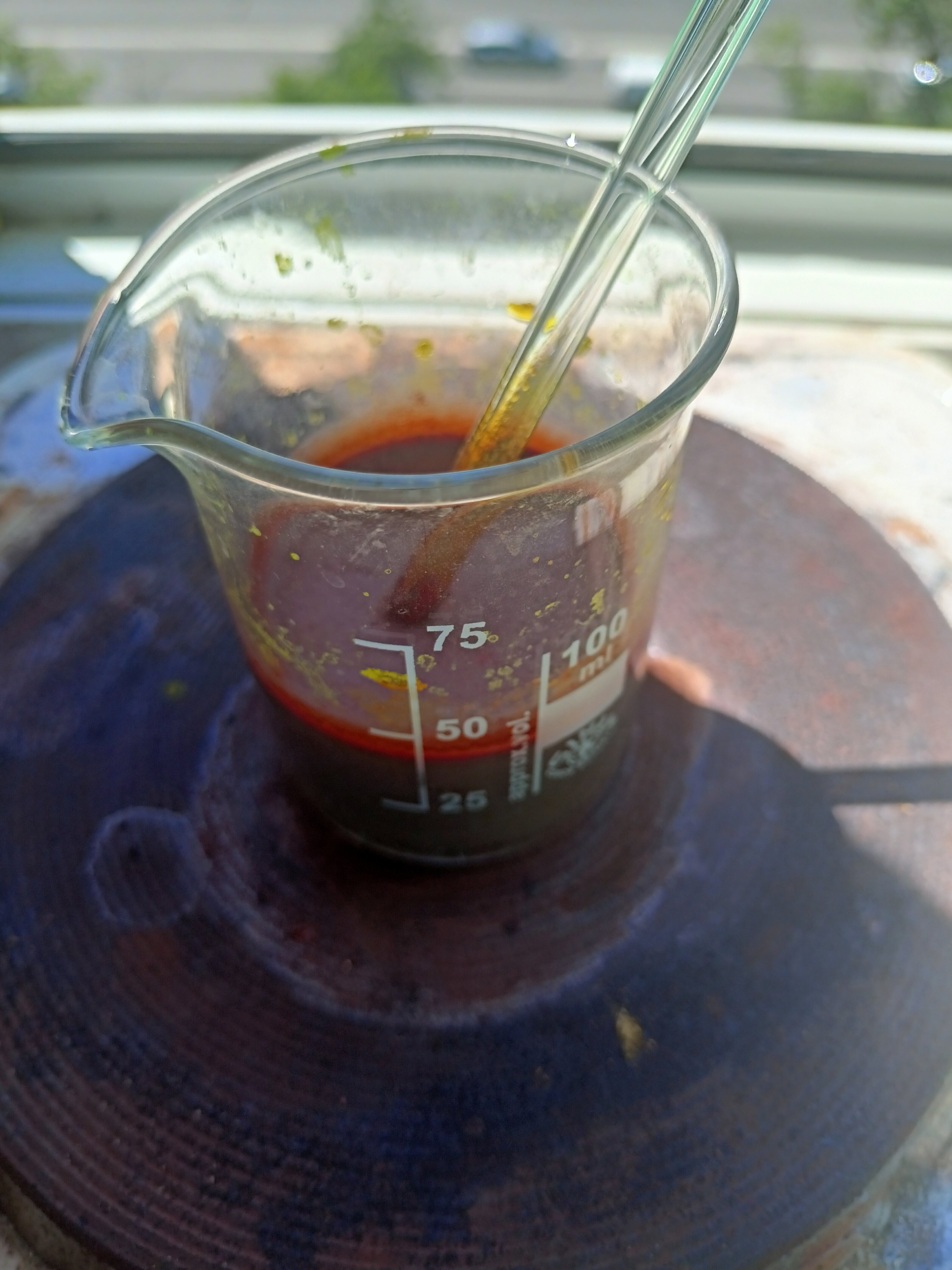 A beaker on a hotplate with a stir rod in it, filled with a dark red suspension.