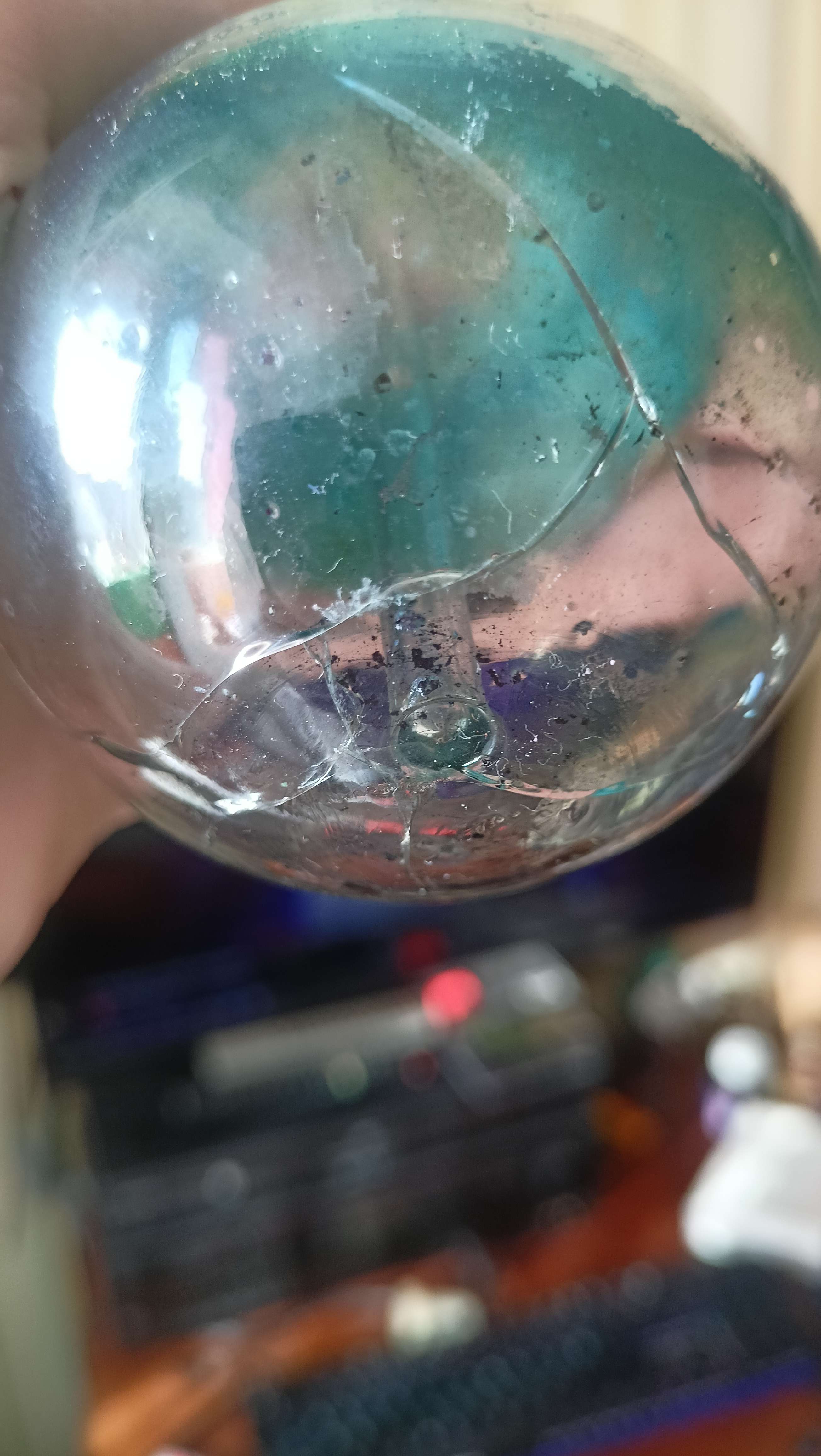 A cracked round bottom flask with a stir rod inside of it slightly covered in blue crystals