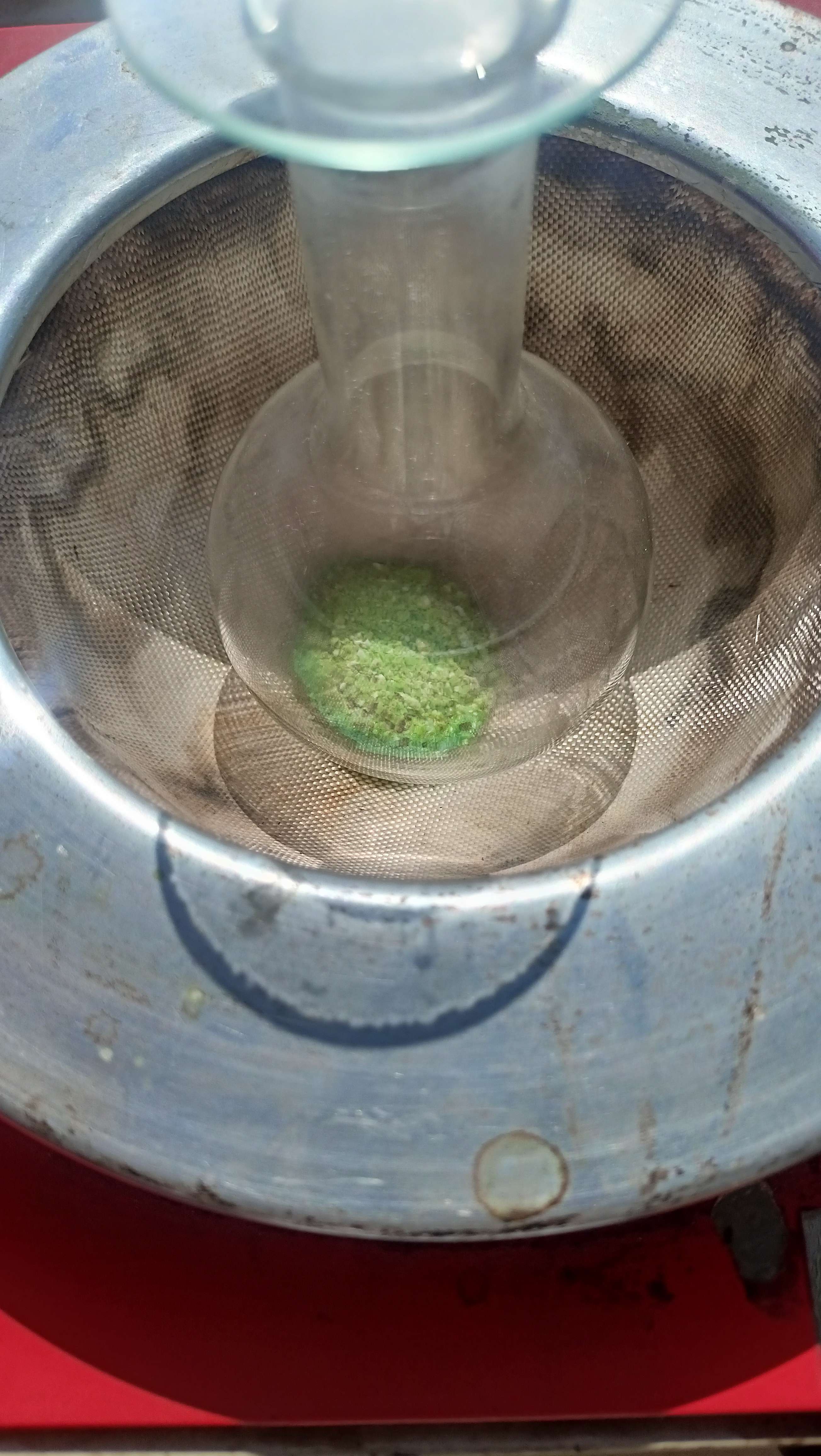 A flask in a heating mantle filled with a greenish white powder