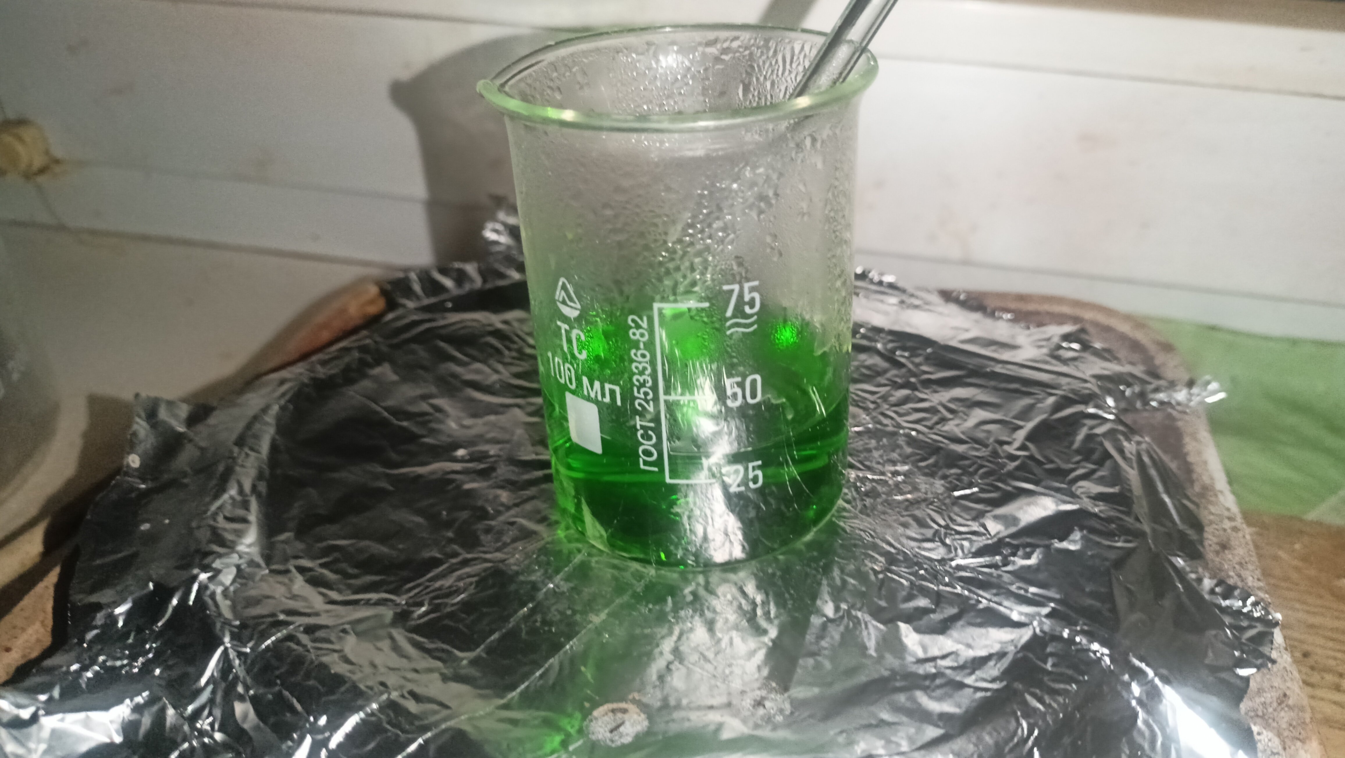 Darkish Green Solution in a 100 ml beaker being evaporated on a hotplate